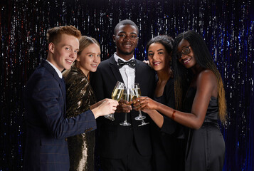 Waist up portrait of multi-ethnic group of friends clinking champagne glasses and smiling at camera while enjoying elegant party © Seventyfour
