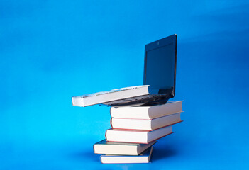 laptop and stack of books on yellow background