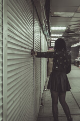 Halloween scary zombie girl standing with her back and watching through the window at night with...