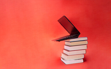 laptop and stack of books on yellow background