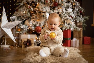 Cute baby girl sitting with Christmas Ball near Christmas trees at home, Happy New year