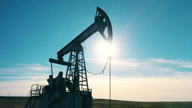 Silhouette of a working oil pumpjack in daylight