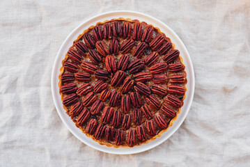 Delicious freshly baked homemade pecan pie on gray concrete background. Top view, flat lay. Popular holiday meal for Thanksgiving and Christmas.