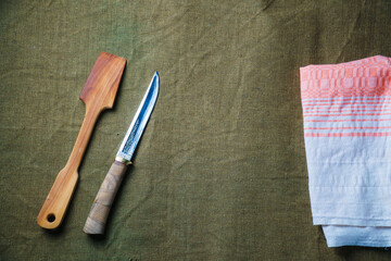 The wooden spatula and knife lie on a green ragcloth next to the napkin.