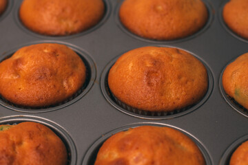 Freshly baked delicious sweet muffins with candied fruits in a baking dish. Homemade cake. Making cupcakes. Close-up
