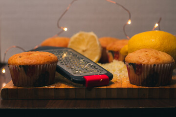 Cooking lemon cupcakes. Ingredients for baking homemade muffins. Juicy yellow lemons, grated lemon zest and Christmas lights. Preparing for the holidays