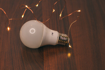 7-watt led energy-saving frosted light bulb and yellow Christmas lights isolated on wooden...