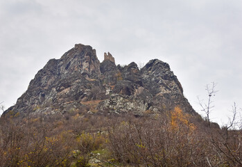 Ruins of Berdiki (Poladauri) castle high up on the hill with overcast sky in the background.