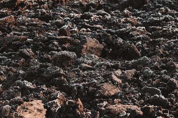 Frozen ground with hoarfrost on a farm field. Focus on frozen soil. Copy, empty space for text. Weather forecast and development time strategy for sowing growing crops