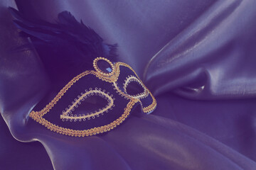 Fototapeta premium Photo of elegant and delicate Venetian mask over dark silk background. Vintage filter