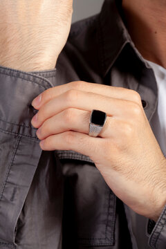 Black stone silver men's ring, ring attached to the finger of the left hand of the gray shirt male.