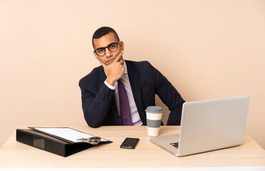 Young business man in his office with a laptop and other documents thinking
