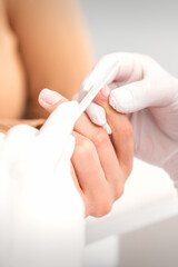 Close up of a manicurist files the female nails with the nail file in a nail salon
