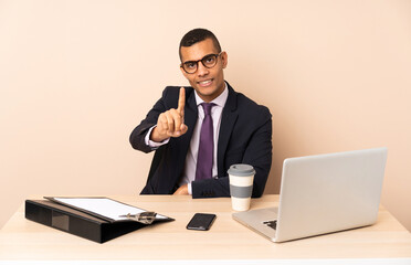 Young business man in his office with a laptop and other documents showing and lifting a finger