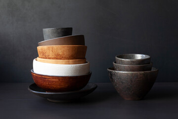 Still life with handmade ceramic dishware on a black background. Plates, bowls, pialas. Rustic style. - obrazy, fototapety, plakaty