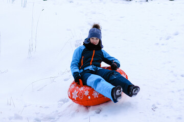 A cute teenage girl having fun on snow tube on a winter day. Wintertime, entertainment, activity, childhood, holidays concept.