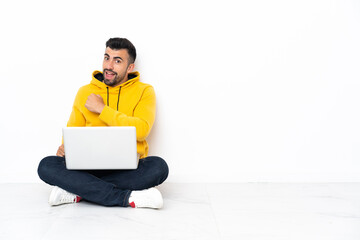 Caucasian man sitting on the floor with his laptop celebrating a victory