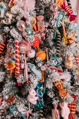 Christmas gifts for kids under the tree. Christmas tree decorated with toys and colorful candy canes and sweets. Present boxes under the christmas tree.