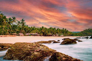 Long exposure. Beautiful and relaxing beach flanked by green palm trees at sunset. Varkala, Kerala,...