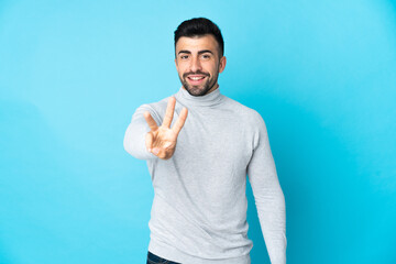 Caucasian man over isolated blue background happy and counting three with fingers