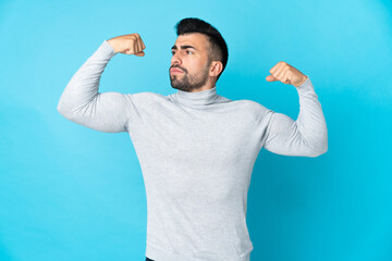 Caucasian man over isolated blue background doing strong gesture
