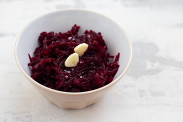 boiled beet with garlic in the bowl on ceramic background