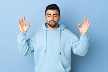 Fototapeta premium Caucasian man over isolated blue background in zen pose
