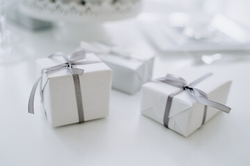 Christmas White Gift Boxes Decorated Ribbon and Bow-knot Close-up Photography. Wrapping Blank Packages Lying on Table. New Year or Birthday Present Packaging, Holiday Celebration Accessories