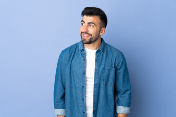 Caucasian man over isolated blue background looking to the side and smiling