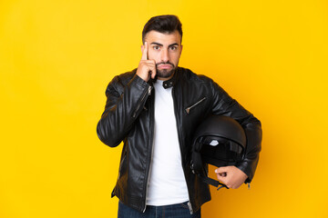 Caucasian man with a motorcycle helmet over isolated yellow background thinking an idea