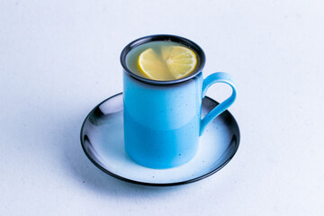 Ginger tea with lemon in a blue ceramic mug isolated on a white background close up.