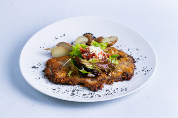 Veal milanese in a white plate isolated on a white background close up.