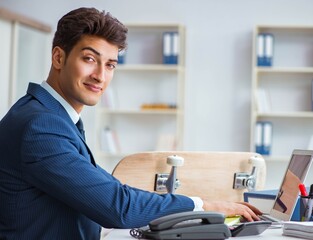Fototapeta premium Young businessman with skate in office in sports concept