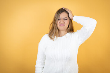 Young caucasian woman over isolated yellow background putting one hand on her head smiling like she...