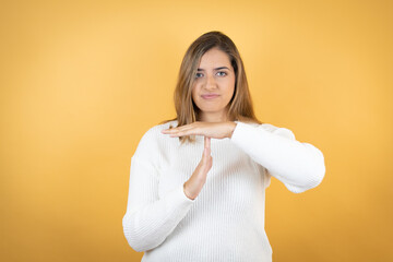 Young caucasian woman over isolated yellow background Doing time out gesture with hands, frustrated...