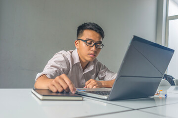 The Asian young man feeling sleepy and tired at workplace