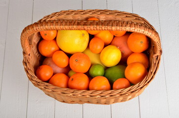 Various citrus fruits in a wicker basket on a white board