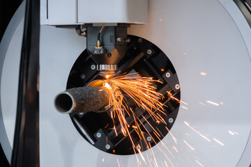 Automatic cnc laser cutting machine working with cylindrical metal workpiece with sparks at factory, plant. Metalworking, machining, industrial, equipment, technology, manufacturing concept