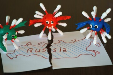 Figures of multi-colored viruses made of plasticine. Next to the torn map of Russia.