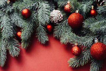 Naklejka na ściany i meble Christmas red decorations, fir tree branches on red background. Flat lay. Nature Christmas concept. Flat lay, top view, copy space