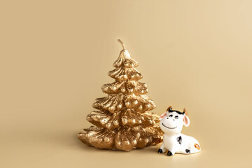 Bull symbol of the new year 2021. Ceramic small figurine of cute white bull and golden christmas fir tree on pastel background. Copy space.