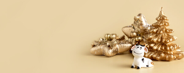 Bull symbol of the new year 2021. Ceramic small figurine of cute white bull, golden christmas fir tree and christmas decoration of star shape on pastel background. Copy space.