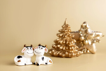 Bull symbol of the new year 2021. Ceramic small figurine of cute white bull, golden christmas fir tree and christmas decoration of star shape on pastel background. Copy space.