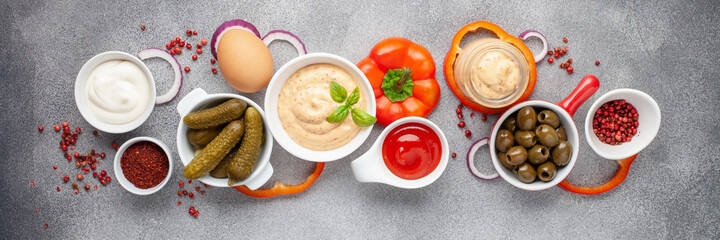 Thousand Islands sauce and ingredients - cucumbers, onions, paprika, ketchup and mayonnaise in bowls on the table. American cuisine, dip for burgers and meat. Top view