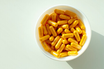 Closeup curcuma capsules in white bowl isolated on white background. Top view.