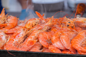 Process of cooking fresh red langoustine shrimps, prawns on grill at summer local food market - close up. Outdoor cooking, barbecue, gastronomy, seafood, cookery, street food concept