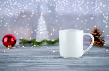 Obraz na płótnie Canvas White cup of coffee or tea and Christmas decoration on wooden table near window. Holiday time at home