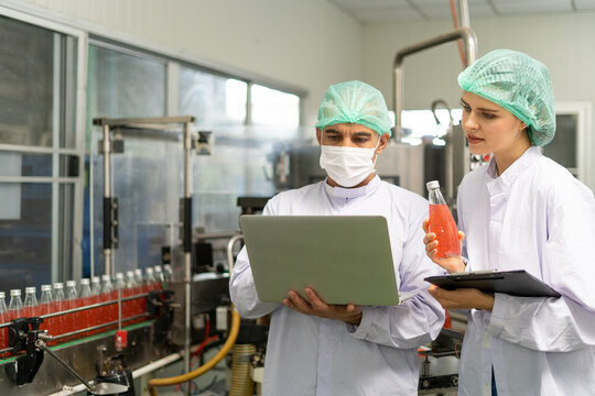 Female quality inspection hold a non-standard juice bottle. The Prince records the mistake of an ambush to keep a record of product. Processed fruit juice and production quality inspection.
