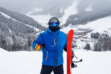 Fototapeta na wymiar Close up portrait guy holding red snowboard in winter