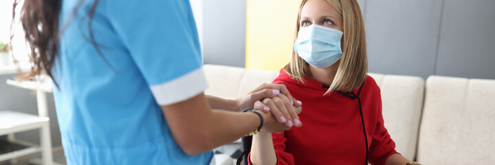 Doctor in uniform holds hand of sick young woman in wheelchair portrait. Psychological assistance...